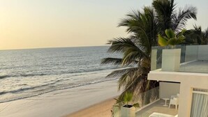 Uma propriedade moderna à beira-mar com piscina, móveis de exterior brancos e palmeiras.