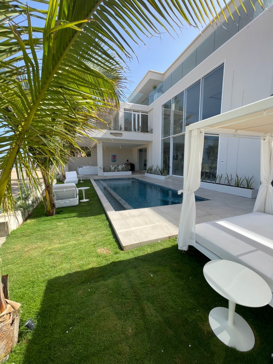 Une maison moderne dotée d’une piscine, d’un patio couvert et d’une pelouse.