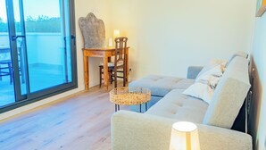 Una sala de estar moderna con un sofá, una mesa de madera y una silla, y un ventanal grande.