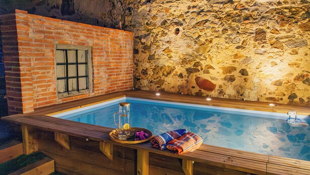 Una terraza de madera con un muro de piedra y un edificio de ladrillo.