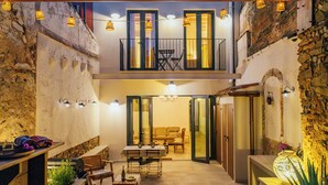 Un patio con zona de comedor, sofá y mesa. Hay puertas que conducen a otras habitaciones.