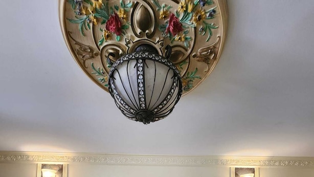 A hotel room with a large bed, a decorative ceiling light, and a stone-patterned headboard. - Westview Motel (North Bergen)