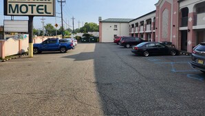 A Westview Motel with a parking lot, multiple cars, and a building with a pink facade. - Westview Motel (North Bergen)