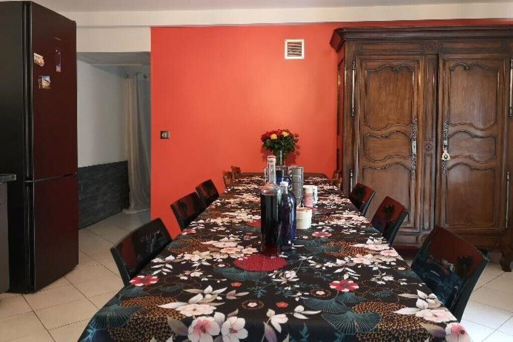 A dining area with a long table set for six, surrounded by chairs.