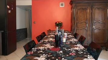 A dining area with a long table set for six, surrounded by chairs.