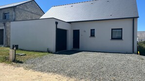 Ein modernes Gebäude mit weißer Fassade, einem geneigten Dach und einer Zuwegung mit Kies.