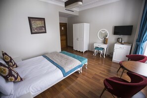 A hotel room with a bed, a desk, a wardrobe, a TV, and a chair. - The Void Hotel (Istanbul)