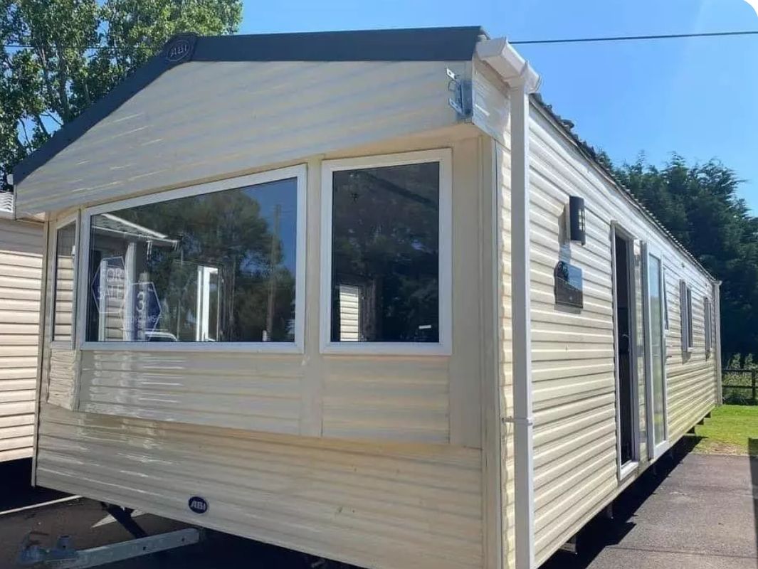 A mobile home with a front door, two windows, and a small porch area.
