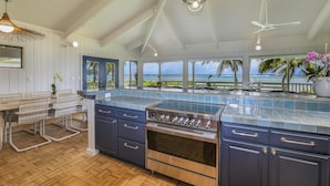 Un'ampia cucina con un'isola grande, forno a incasso e vista sull'oceano.