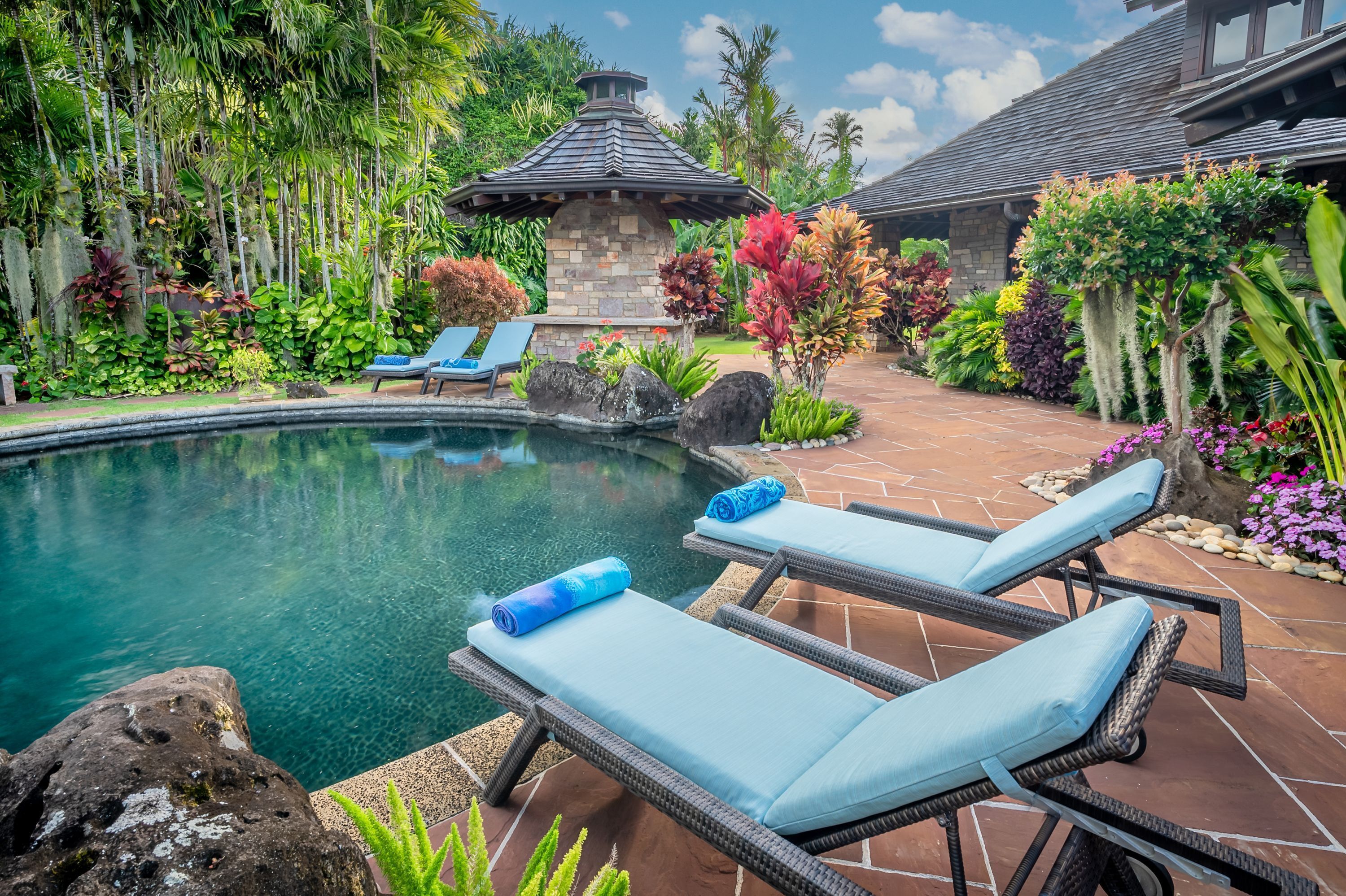 Un espace piscine avec des chaises longues et une structure en pierre.