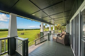 En inglasad veranda med utsikt över en grön gräsmatta och en klar himmel.