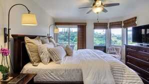 A bedroom with a large bed, a ceiling fan, and a TV. - Hanalei Bay Villa 8 (Princeville)