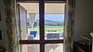 Et værelse med en skydedør, der fører ud til en udendørs terrasse med et bord og stole.