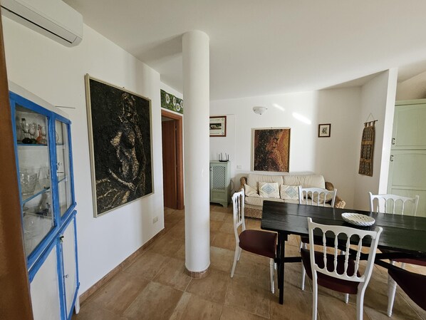 A dining area with a table and chairs, a sofa, and a cabinet with glass doors.