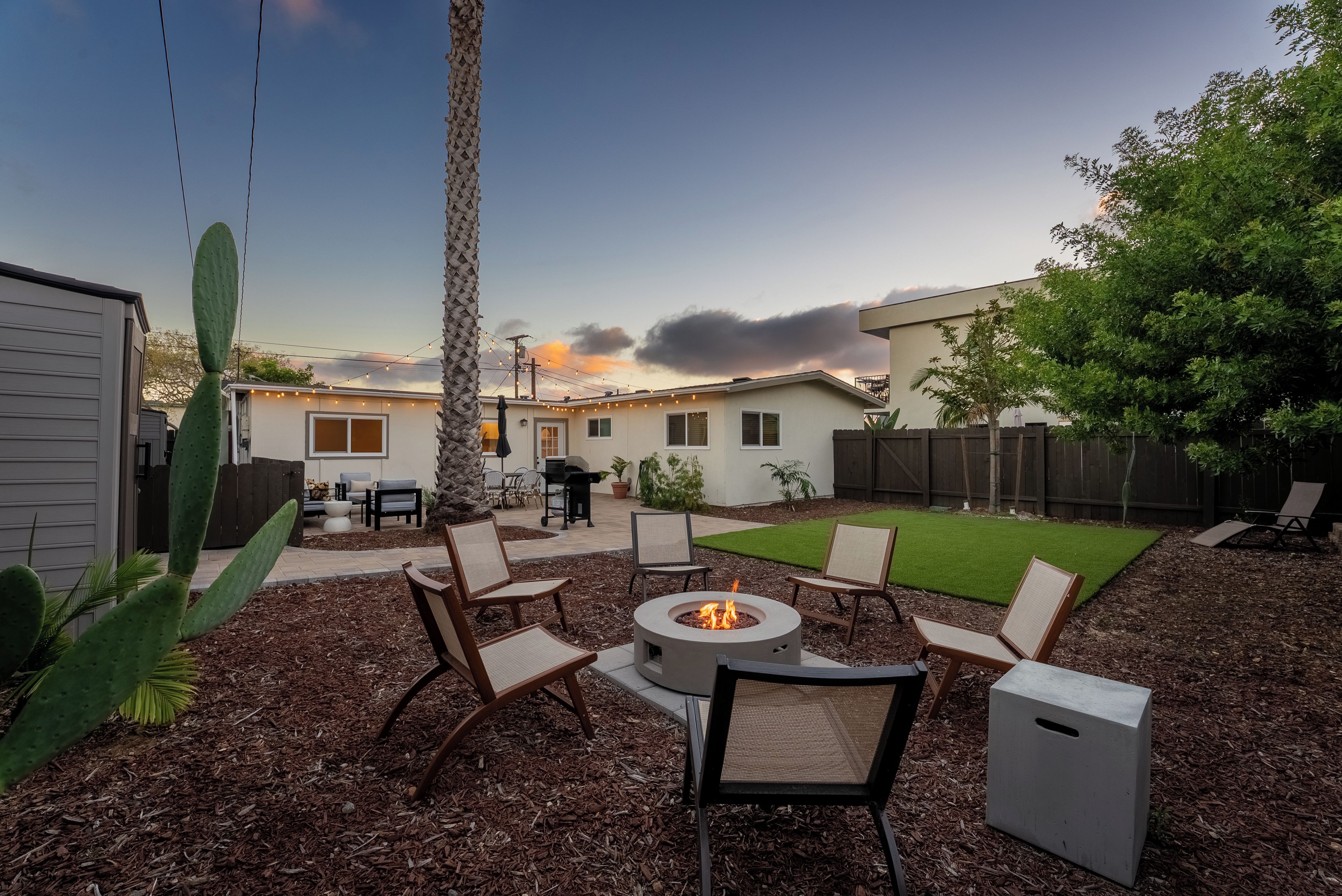 A backyard with a fire pit, outdoor furniture, and a patio area.