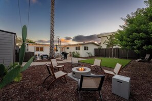 Ein Garten mit Feuerstelle, Gartenmöbeln und einer Terrassenfläche.