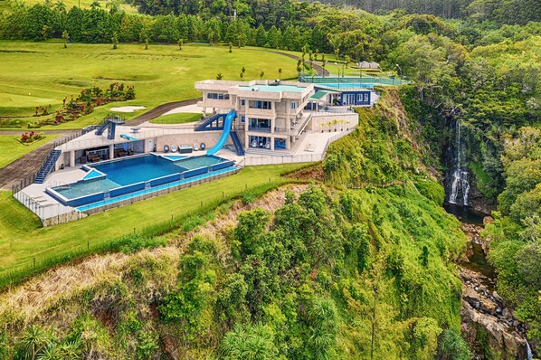 A resort with a large pool, a waterfall, and lush greenery.