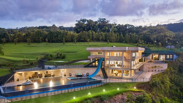 Une maison moderne dotée d’une grande piscine, d’un toboggan et d’une pelouse bien entretenue.
