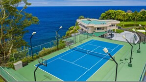 Un court de tennis avec vue sur l’océan et un bâtiment doté d’un toit végétalisé.
