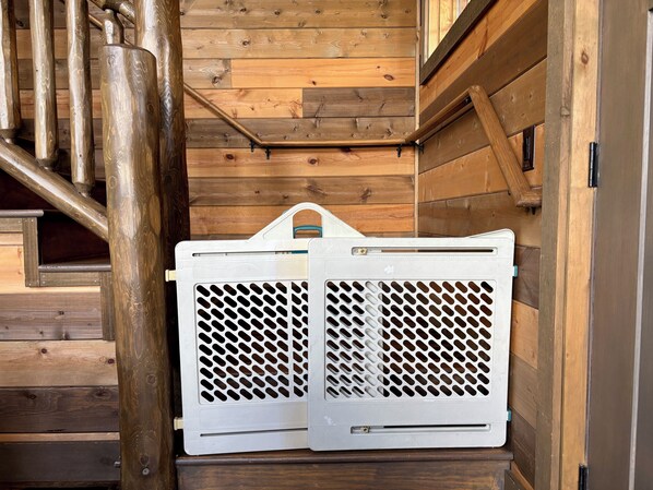 A wooden staircase with a white laundry basket hanging on the wall.