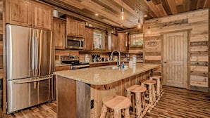 A modern kitchen with wooden cabinetry, stainless steel appliances, a granite countertop, and bar stools.