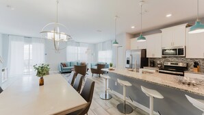 A modern kitchen with white cabinets, a central island, bar stools, and pendant lighting. - Last Minute Disney Getaway! Private Pool & Themed Bedrooms. Book Now! #122403 (Orlando)