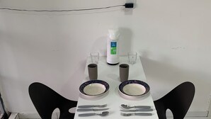 Une table à manger avec deux chaises, un distributeur d’eau et une prise électrique au mur.