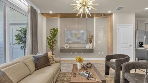 Un salon moderne avec un canapé beige, une table basse en bois et un téléviseur fixé au mur.
