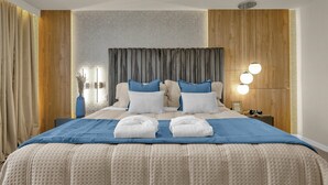 Une chambre d’hôtel moderne avec un grand lit, des murs lambrissés et une table de chevet avec une lampe.