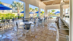 An outdoor patio area with tables and chairs, a pool in the background, and palm trees. - Last Minute Disney Getaway! Townhouse with Private Pool. Book Now! #128831 (Orlando)