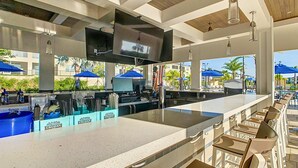 A bar area with a poolside view, bar stools, and a television mounted on the ceiling. - Last Minute Disney Getaway! Townhouse with Private Pool. Book Now! #128831 (Orlando)