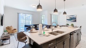 A modern kitchen with a central island, black cabinets, and pendant lighting. - Last Minute Disney Getaway! Townhouse with Private Pool. Book Now! #128831 (Orlando)