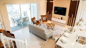 Un salón amplio con sofá, sillas, una mesa de comedor y una cocina con encimera de granito y fregadero de acero inoxidable.