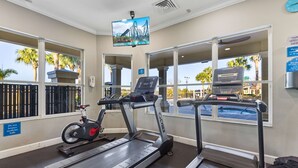 A fitness center with treadmills, an exercise bike, and a TV screen displaying a roller coaster.