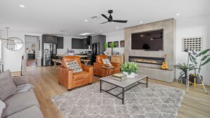 Una sala moderna con chimenea, sillones de cuero, una mesa de centro y un televisor montado en la pared.