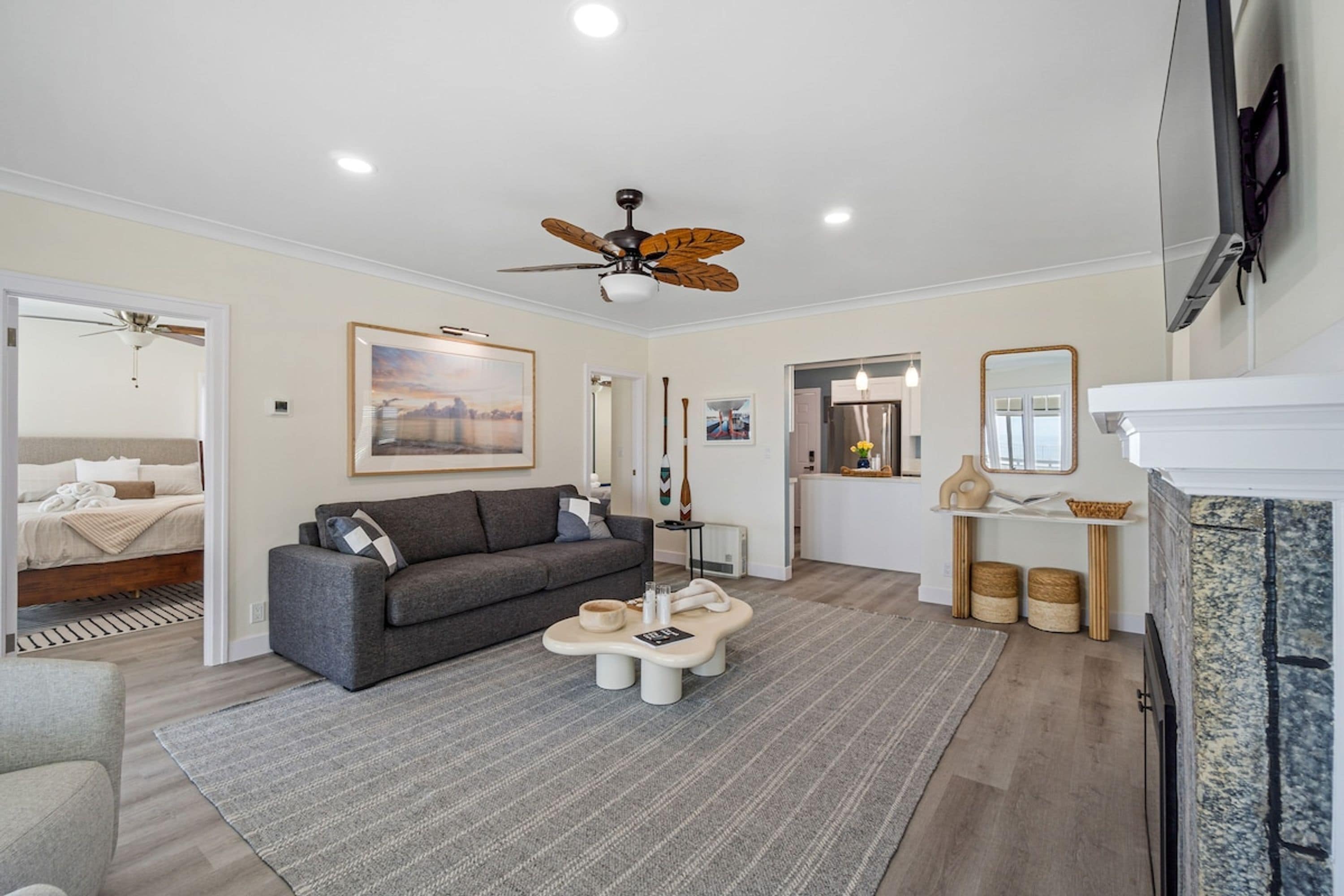 A modern living room with a gray sofa, a coffee table, a ceiling fan, and a fireplace.
