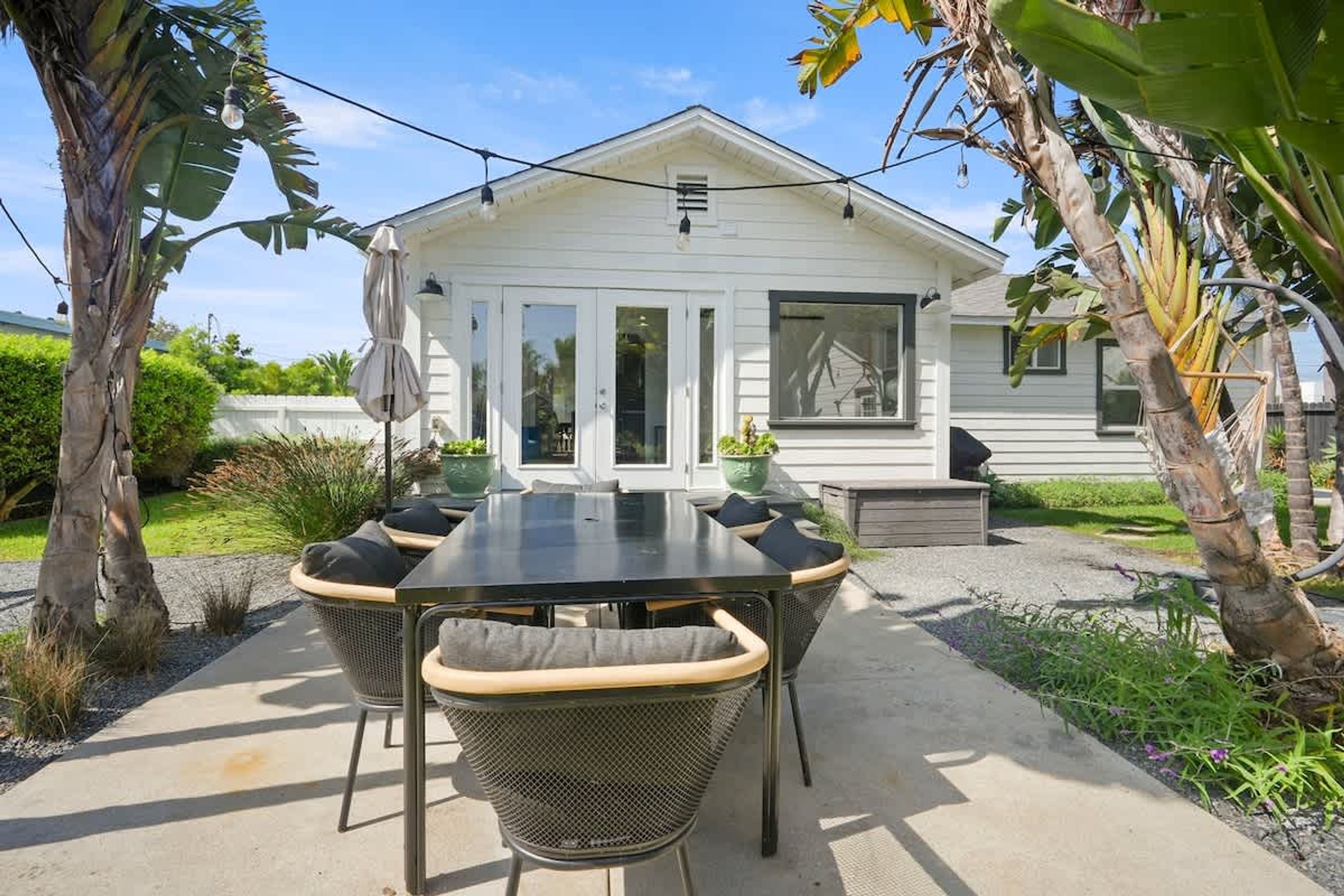 Una casa con patio, mobili da esterno e giardino.