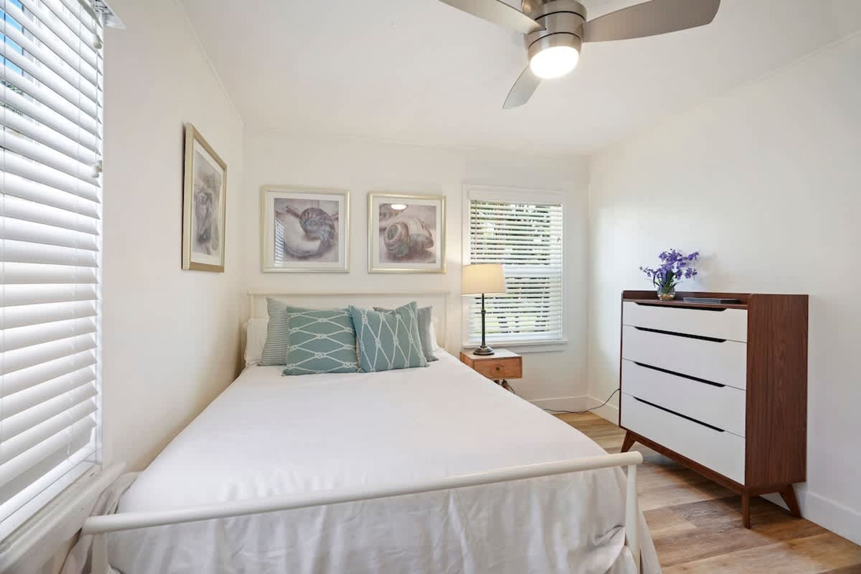 Une chambre à coucher comprenant un lit, une table de chevet, une commode et trois tableaux encadrés accrochés au mur.