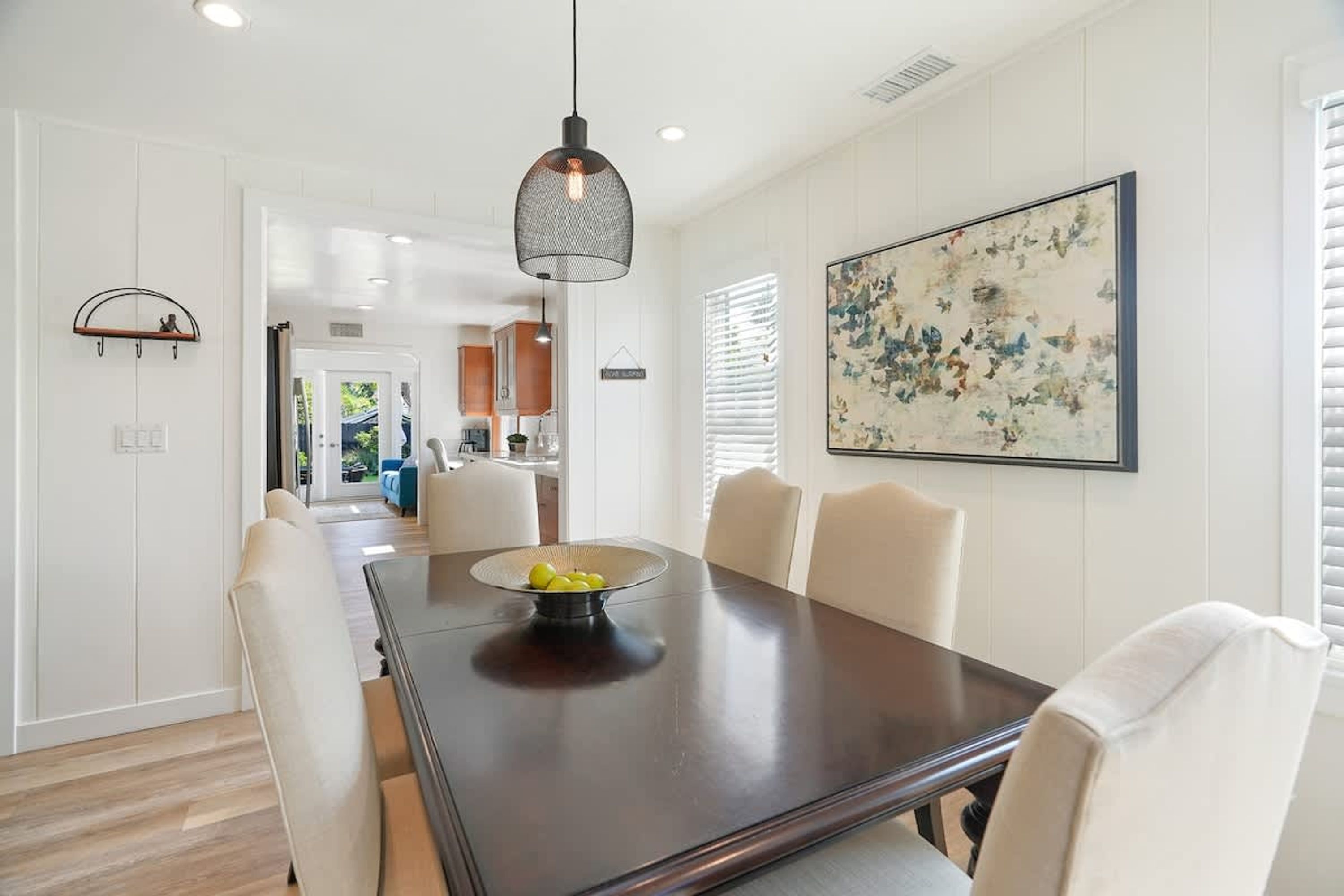 A dining area with a dark wooden table, white chairs, and a hanging pendant light.