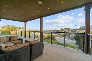 A balcony with wicker furniture and a view of a road and buildings. - Dana Point Luxe Str14-007 (Dana Point)