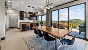 A modern kitchen with a dining area, large windows, and a view of the outdoors. - Dana Point Luxe Str14-007 (Dana Point)