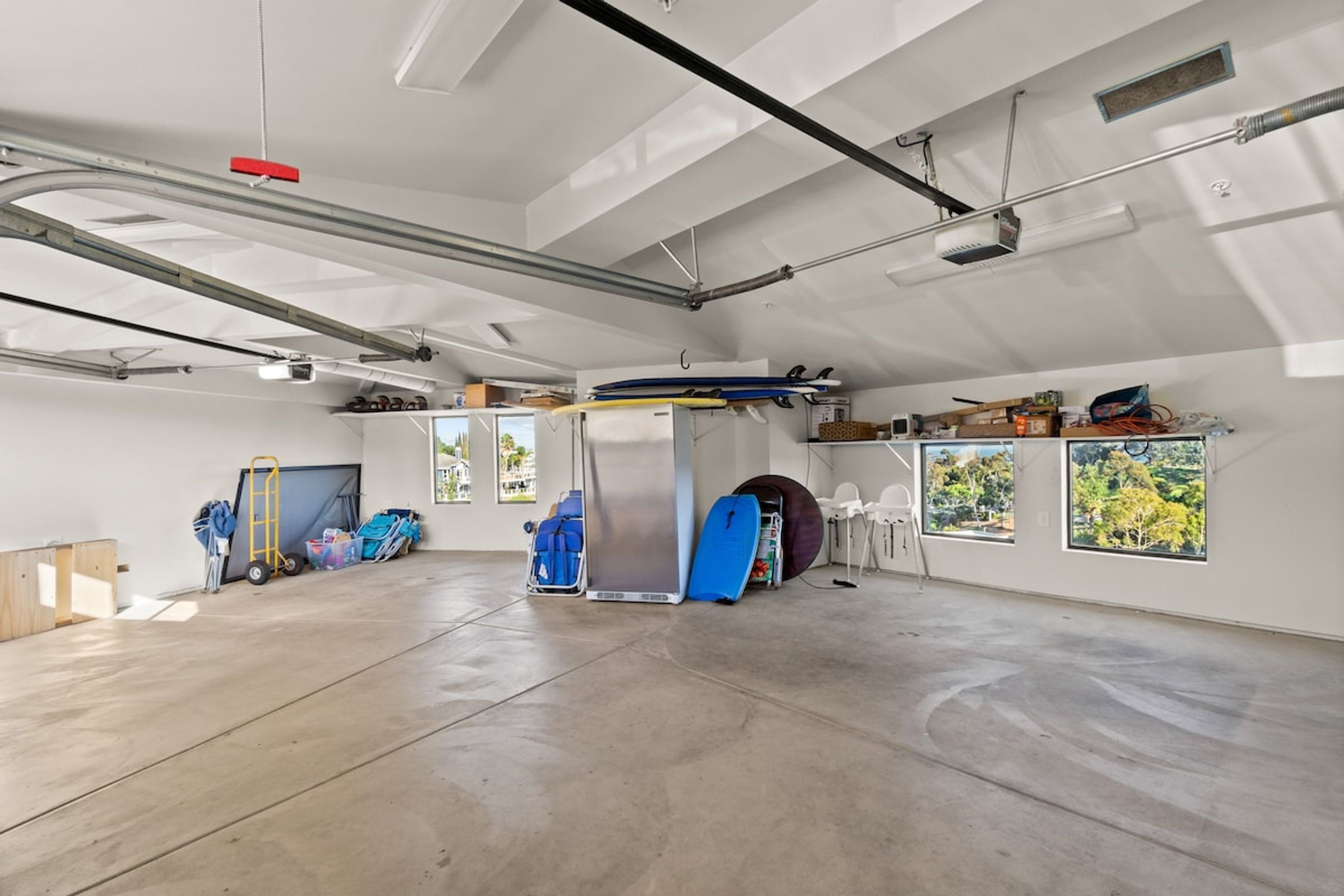 A spacious garage with concrete floors, a large workbench, and various tools and equipment.