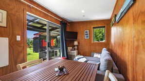 A wooden interior with a dining table, a sofa, and a TV mounted on the wall.