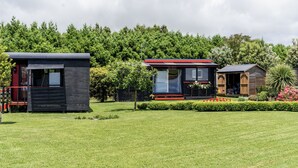 A modern, compact building with a flat roof, surrounded by a well-maintained lawn and dense trees.