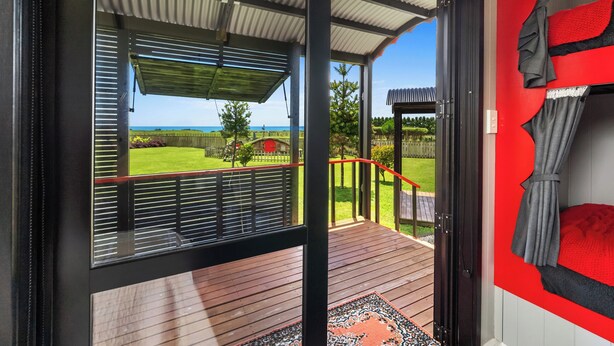 A room with a view of a grassy area and a red fence.
