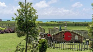 A fenced area with a wooden structure, a Christmas tree, and a view of the sea.