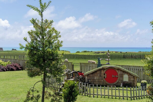 Un espace clos, délimité par une clôture, avec une structure en bois, un sapin de Noël et une vue sur la mer.