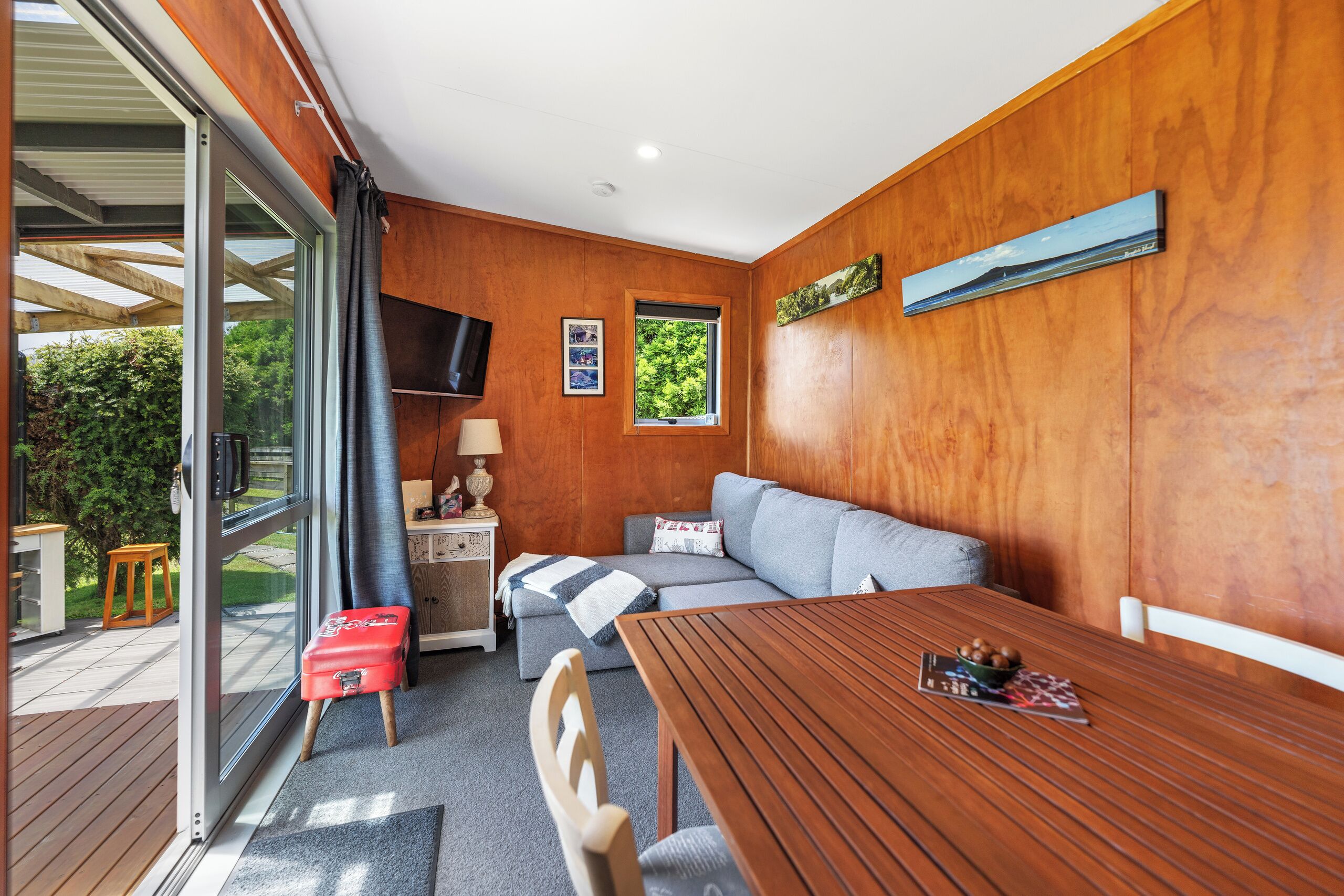 Ein gemütliches Zimmer mit Holzvertäfelung, einer Couch, einem Tisch mit Obstschale und einem Fernseher.