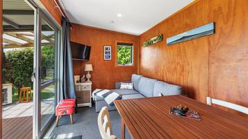 Ein gemütliches Zimmer mit Holzvertäfelung, einer Couch, einem Tisch mit Obstschale und einem Fernseher.