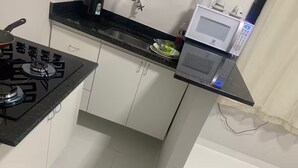 Una cocina compacta con estufa a gas, microondas y pileta.